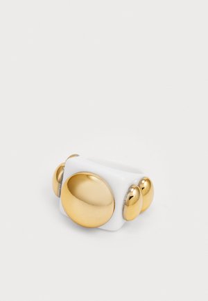 White ring featuring a glossy finish with a large gold circular accent and three smaller gold spheres on one side. Smooth texture.