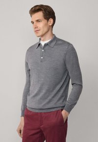 Grijze gebreide polo met lange mouwen en een kraag, voorzien van drie knopen bij de hals en geribbelde manchetten, gecombineerd met bordeauxrode broek.