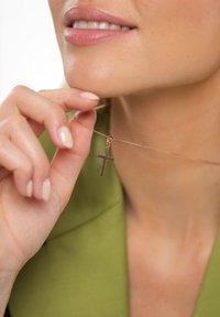 Roosa kullaga kaelakee ripats peenel kettal, hoitud lähedal rangluule. Taust on neutraalne ning ripatsil on läikiv viimistlus.