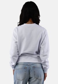 Light gray sweatshirt with long sleeves, ribbed cuffs, and a crew neckline, paired with light blue jeans featuring back pockets.