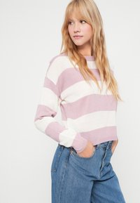 Pull rayé rose clair et blanc, texture tricotée, encolure ronde, coupeLoose, associé à un jean taille haute bleu, style décontracté.