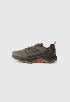Scarpa da trail running in verde oliva e nero. Presenta una tomaia in rete e gomma, dettagli arancioni e una suola zigrinata con tacchetti per la trazione.