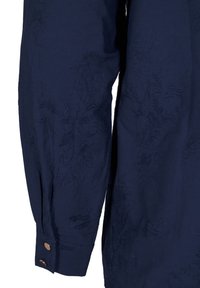 Mörkblå skjorta med broderade blommönster, med en knäppt manschett och en texturerad yta. Skräddarsydd passform med sidoklyftor.