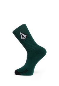 Chaussette mi-haute côtelée vert foncé avec un orteil noir et un logo géométrique blanc sur la cheville, texte noir près de la zone des orteils.