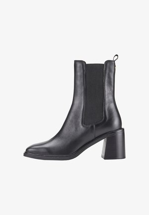 Bottine en cuir noir avec des panneaux élastiques ribbés sur les côtés, bout pointu et talon carré, dotée d'une languette à l'arrière.