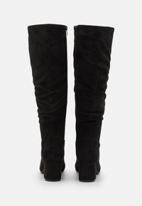 Bottes noires hauteur genou en suède souple. Présentent un design froissé, un talon bloc haut et une fermeture éclair à l'arrière.