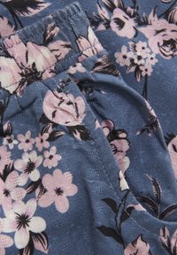 Blumenmusterstoff in Blau mit pinken und schwarzen Blumen. Weicher Stoff mit elastischem Bund, der auf Taillenhöhe gerafft ist.