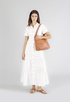 Witte button-up jurk met korte mouwen en tiered zoom, gecombineerd met een bruine leren schoudertas en platte sandalen met straps.