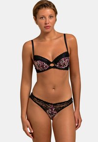 Ensemble de lingerie avec un soutien-gorge en dentelle noire aux bonnets à motifs floraux et un string en dentelle assorti, tous deux avec des bords délicats en feston.