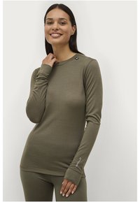 Olijfgroene shirt met lange mouwen en een getailleerd ontwerp, ronde halslijn en duimgaten. Heeft een logo dat op de schouder is genaaid. Zachte textuur.