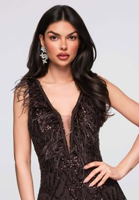 Robe noire avec accents de plumes aux épaules, ornée de sequins, décolleté en V profond et détail en tissu transparent. Boucles d'oreilles assorties incluses.