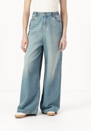 Jean en denim bleu à jambes larges et taille haute, avec une fermeture à bouton, un délavage subtil et des poches latérales. Texture douce et coupe décontractée.