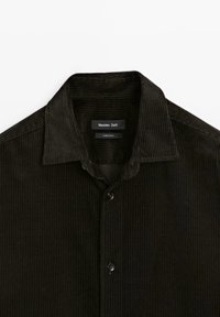 Mørkebrun kordfløjlsskjorte med krave, lodret ribbet tekstur ogknaplukning foran. Mærket lyder "Massimo Dutti."