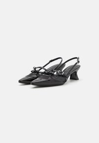 Musta slingback-kengät, joissa on terävä kärki, kiiltävä nahkapinta, teksturoidut yksityiskohdat ja pieni lohkokorko. Varustettu säädettävillä hihnoilla.