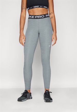 Leggings Nike Pro en gris chiné, ajustés avec des coutures plates. Comprend une taille noire avec un texte "Nike Pro" répété et un petit logo.