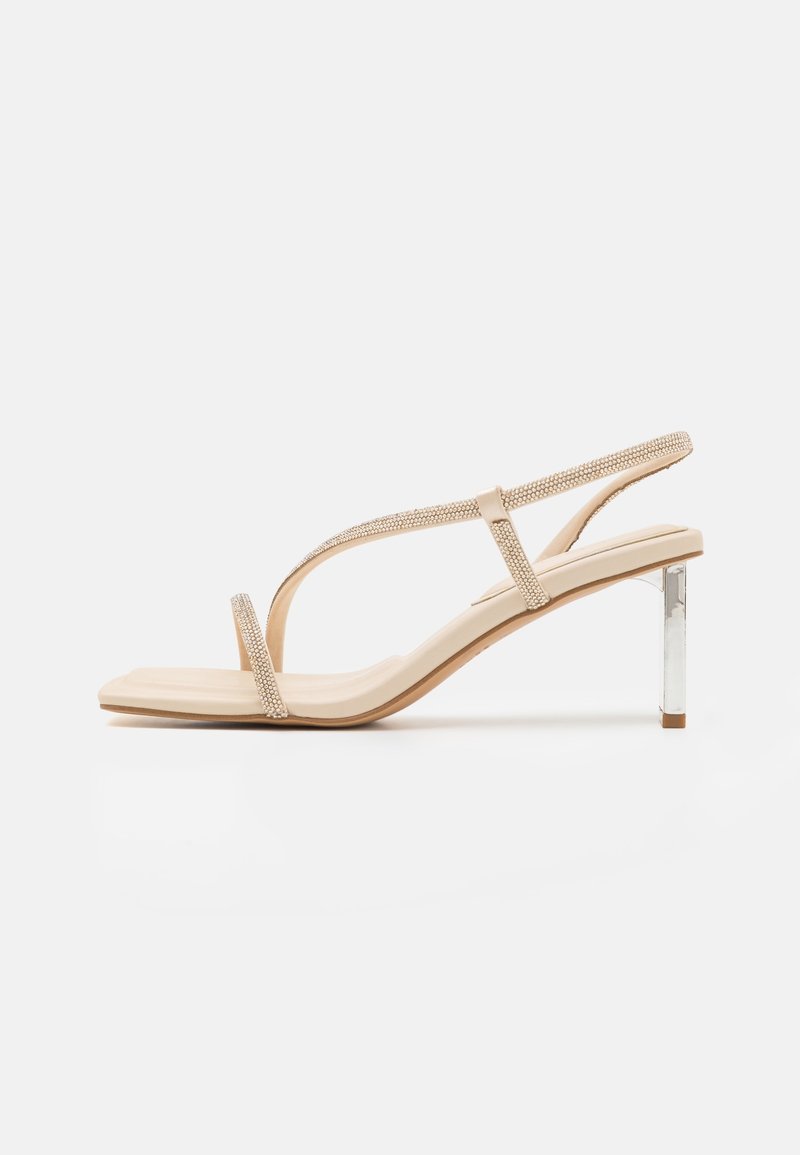 Sandales à talons nudes avec un design à fines lanières, des accents en strass et un talon transparent en bloc. Matériau lisse avec un bout carré.