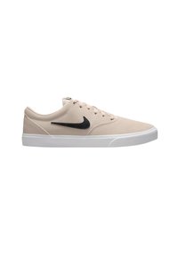 Zapatillas Nike de ante beige claro con el logo Swoosh negro, suela de goma blanca y cinco ojales para los cordones. Diseño simple y de perfil bajo.