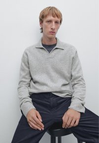 Lichtgrijze, gebreide pullover van een wolmix met een kraag, geribbelde manchetten en een ontspannen pasvorm. Gecombineerd met donkerblauwe corduroy pants. Minimalistische stijl.