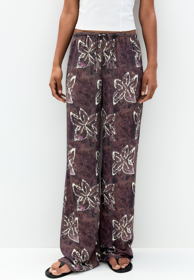 Pantaloni larghi a fantasia viola realizzati in tessuto morbido, con disegni floreali bianchi e una vita elastica con cordino.