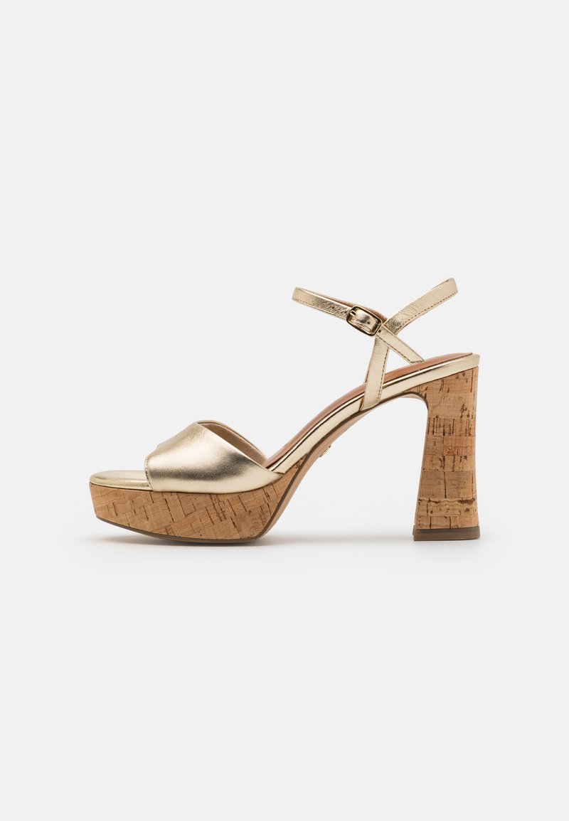 Gold metallic platform sandals with a cork block heel, open toe design, and an adjustable ankle strap for secure fit. Smooth texture.