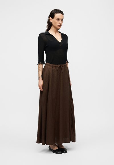 Μαύρο πλεκτό τοπ  με v-λαιμόκοψη και κοντά μανίκια, συνδυασμένο με καφέ, αέρινη φούστα μάξι με ελαστική μέση και κορδόνι.