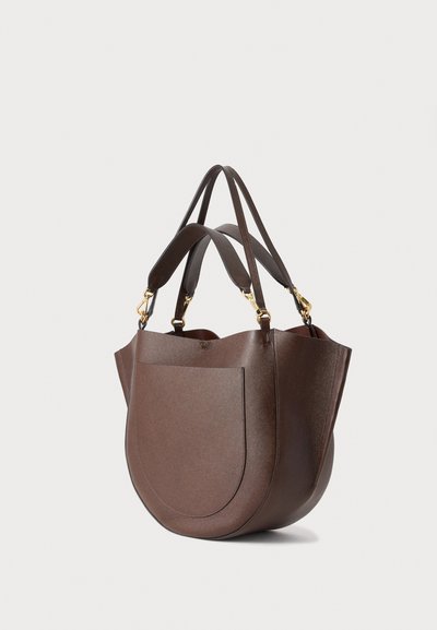 Sac cabas en cuir marron avec poche avant arrondie et doubles bretelles avec fermoirs dorés, présenté sur un fond clair.