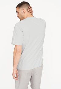 Lys grå crew-neck t-shirt lavet af bomuld, med korte ærmer og en afslappet pasform, parret med lys grå shorts. Subtil struktur synlig.