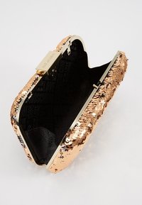 Kopparfärgad paljettclutch med ett guldfärgat metallspänne, med en svart insida som har ett upprepat mönster av texten "Moschino".