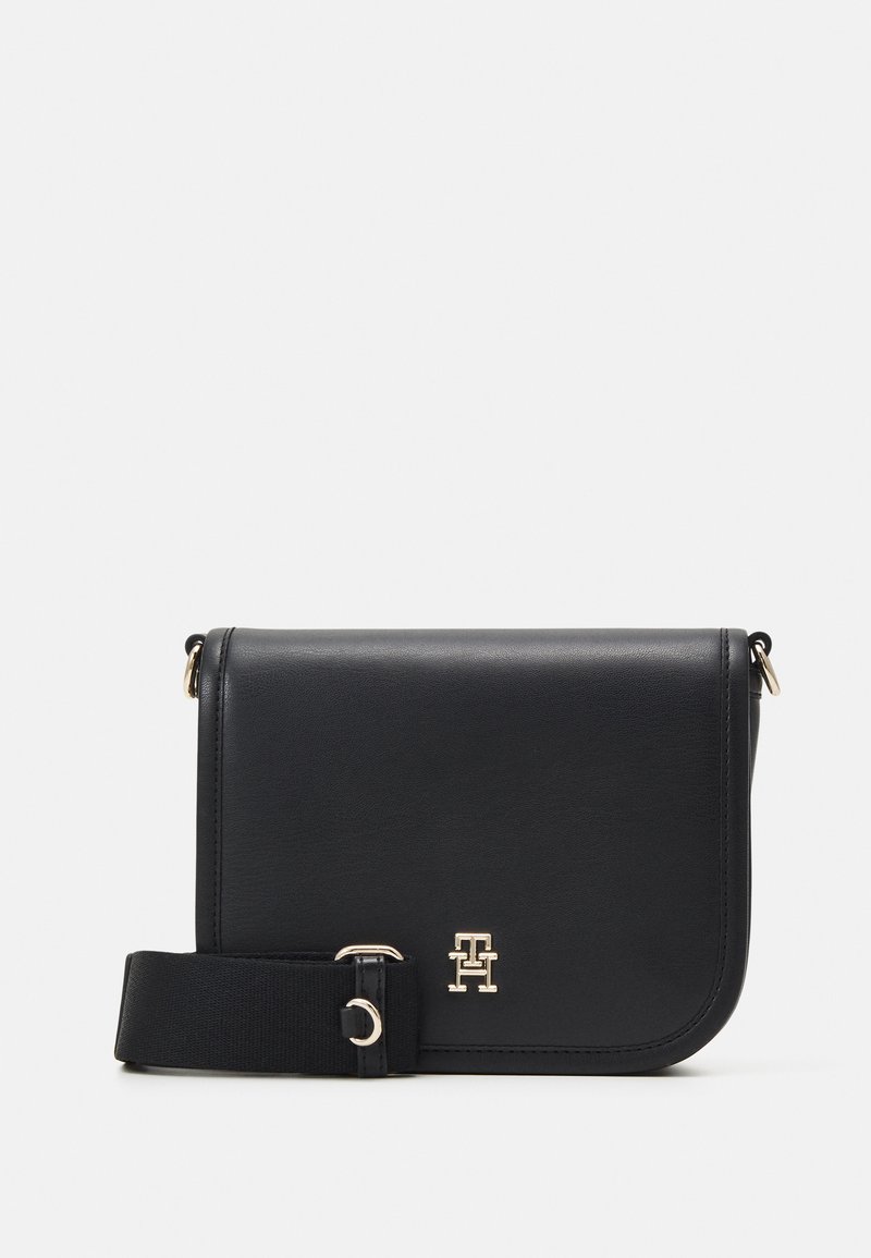 Borsa a tracolla in pelle nera con logo dorato, forma rettangolare e tracolla in tessuto. Texture liscia con bordi angolari e dettagli in metallo dorato.