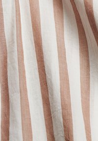 Tissu en lin avec des rayures larges blanches et brun clair alternées, présentant une surface légèrement texturée et une apparence naturelle et respirante.