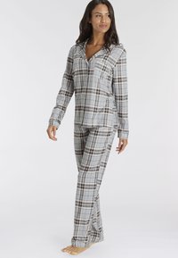 Set di pigiama a quadri grigi composto da una maglia a maniche lunghe con bottoni e pantaloni coordinati. Realizzato in un tessuto morbido con una trama liscia.