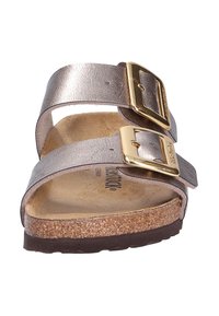 Bronskleurige leren sandalen met twee verstelbare banden en gouden gespen. Korken voetbed met een gestructureerd oppervlak en een donkere rubberen zool.