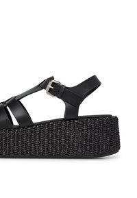Sandali platform neri con suola a trama intrecciata, ampie cinghie in pelle e fibbia regolabile sulla cinghia alla caviglia.