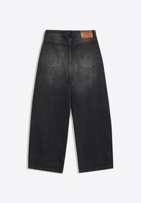 Svarta jeans i jeansmaterial med vida ben, sedda bakifrån med två bakfickor och en brun läderlapp på midjebandet.
