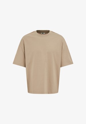 Beige värinen, ylikokoinen lyhythihainen puuvillainen T-paita, jossa on pyöreä kaula-aukko ja pudotetut olkapäät, esillä valkoisella taustalla.