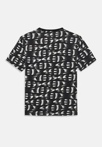 T-shirt noir et blanc à manches courtes avec un motif abstrait ondulé. Tissu doux avec un col rond et une coupe standard.