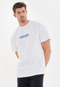 Witte katoenen t-shirt met een blauwe "OREGON" grafische print op de voorkant. Korte mouwen, ontspannen pasvorm en ronde hals.