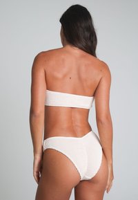 Krämfärgad bikini med en texturerad bandeau-top och högmidjade underdelar med ribbad finish och sömlösa kanter.