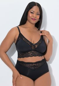 Černá podprsenka a vysoké kalhotky s krajkovými detaily, hladkým materiálem, nastavitelnými ramínky a vlnkovaným krajkovým lemem v pase.