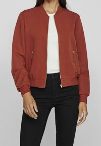 Rostfarbene Bomberjacke aus glattem Stoff mit ribbeltem Kragen, elastischen Bündchen und seitlichen Reißverschlusstaschen.