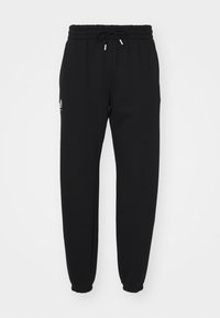 Pantalones deportivos negros hechos de tela suave, con una cintura elástica con cordón, puños elásticos y un pequeño detalle de logo en el costado.