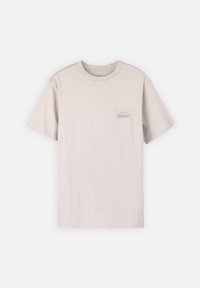 T-shirt en coton beige à manches courtes, col rond, et un petit logo brodé en haut à gauche. Texture douce, coupe standard.