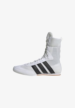 Bota deportiva blanca con parte superior de malla alta, diseño de tres rayas negras y suela de goma. Cuenta con cierre clásico de cordones y cuello acolchado.