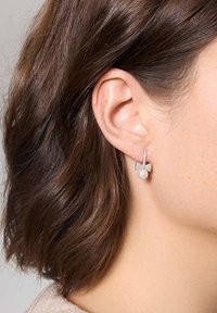 Kolczyki perełkowe z motywem kokardki, z akcentami w srebrnym kolorze oraz osadzonymi cyrkoniami. Kolczyki mają polerowane wykończenie.