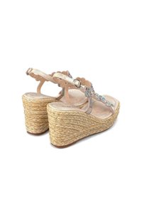 Sandali con zeppa e suola in juta intrecciata, con cinturino nudo decorato da accenti floreali colorati e un design ondulato.