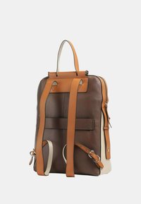 Bruine leren rugzak met beige accenten, voorzien van verstelbare schouderbanden, een handvat aan de bovenkant en een hoofdvak met rits. Gladde textuur, gestructureerd ontwerp.