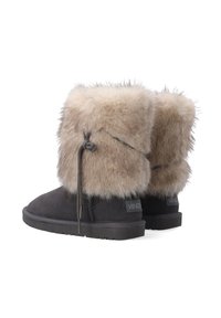 Schwarze Wildlederstiefel mit einem weichen beigen Fellumschlag, der eine gebundene Akzentuierung und eine strukturierte Sohle aufweist. Markenetikett auf die Seite geprägt.
