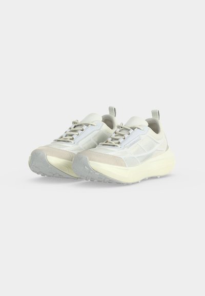 Paire de baskets légères blanche et beige avec semelles épaisses et design à lacets sur un fond clair uni.