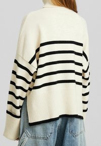 Cremiger Pullover mit schwarzen horizontalen Streifen, ausgestattet mit hohem Kragen, weiter Passform, geripptem Saum und überschnittenen Schultern. Weiche Textur.