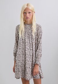 Vestido floral con mangas largas, escote fruncido, fondo beige y estampado de leopardo marrón. Tejido suave con volantes en el dobladillo.